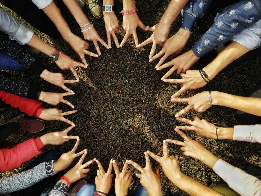 A diverse group of hands forming a star shape in a circle on grassy ground, symbolizing unity.